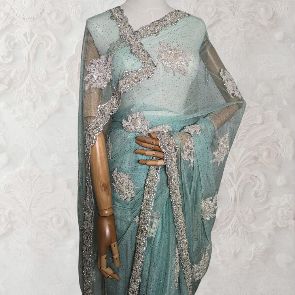 Teal saree with silver embroidery on a mannequin against a white background