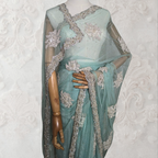 Teal saree with silver embroidery on a mannequin against a white background