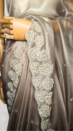Gray saree with floral lace border on a textured white background