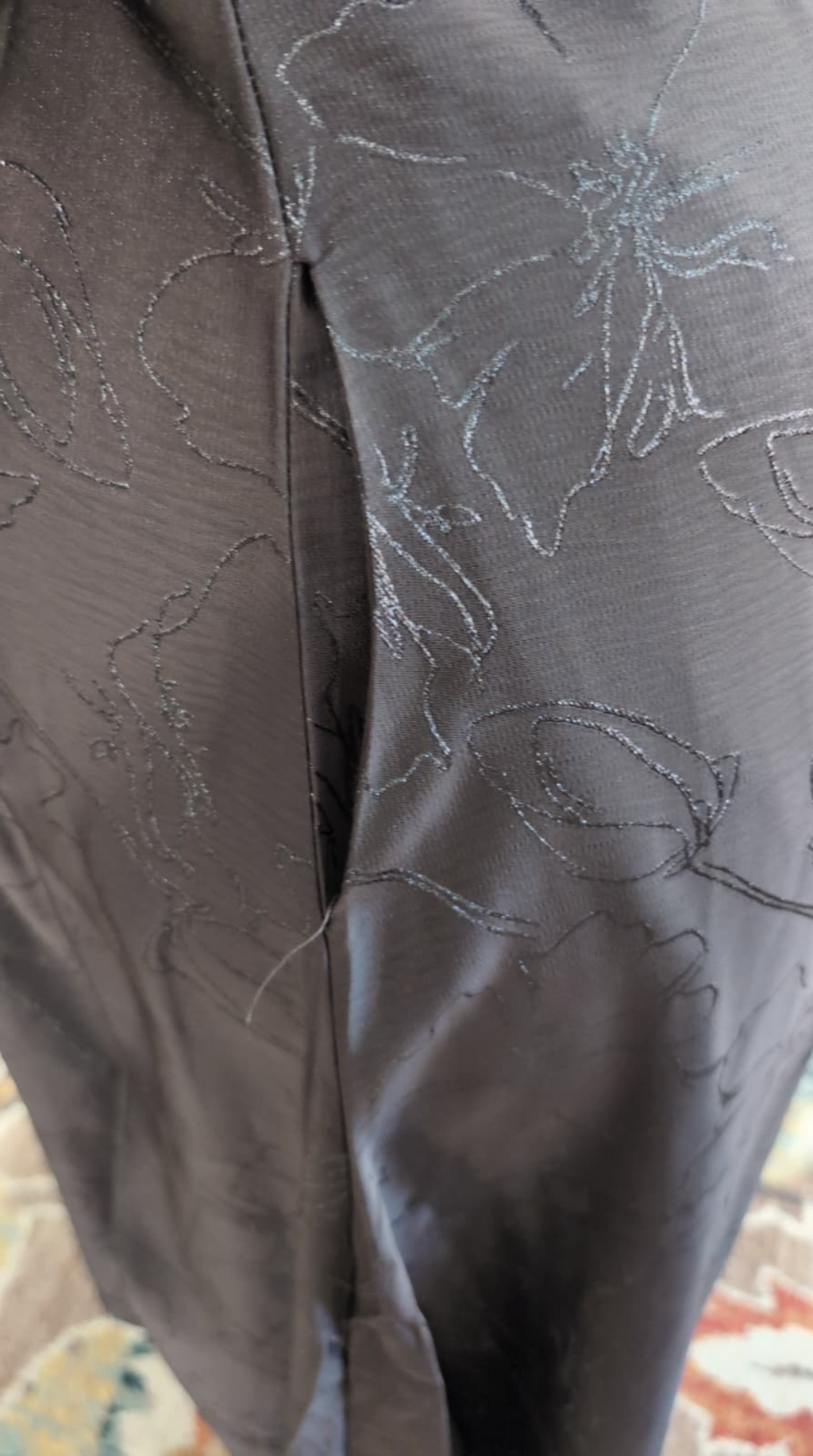 Gray textured fabric with floral patterns on a wooden floor.