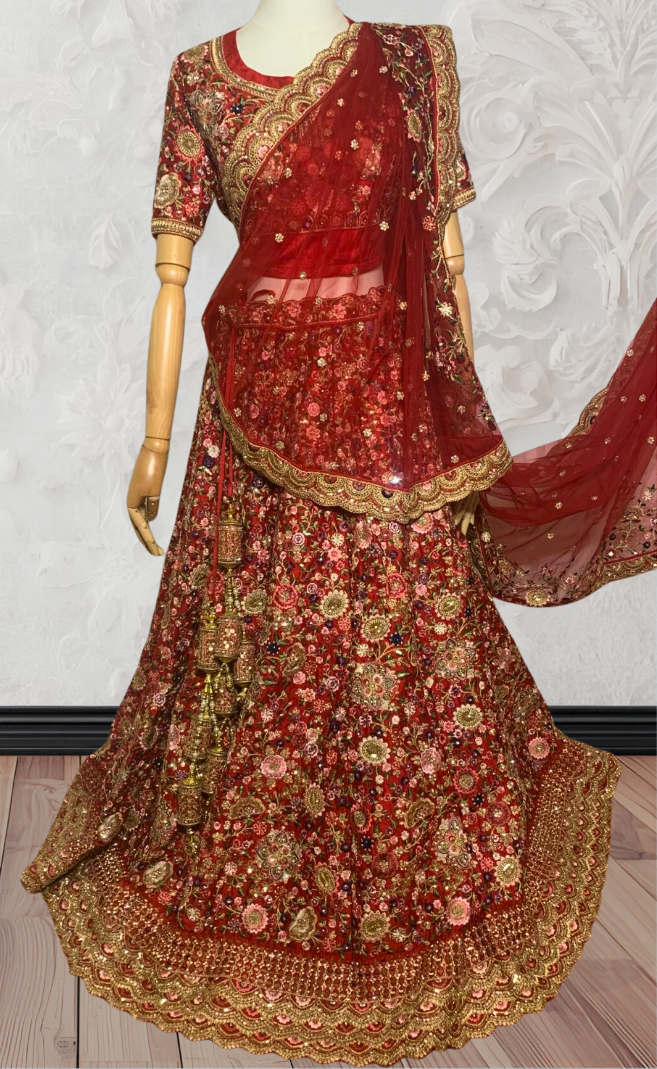 This exquisite red lehenga choli crafted from luxurious raw silk showcases intricate resham, zardosi, beads, sequins, and cut dana floral embroidery. The heavily embellished hemline and delicate cream butti accents enhance its sophisticated charm. Complete with a matching embroidered net dupatta featuring floral buttis and an elegant border, and a stitched blouse piece adorned with coordinating floral motifs, for wedding and bridal, pakistani, bangladeshi, indian, sri lankan.